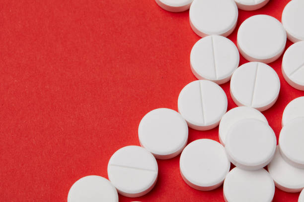 istock A few white round pills on the red paper background. 1003593230