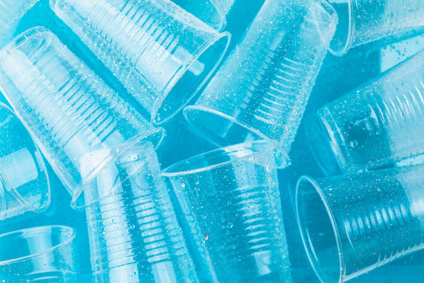 istock Empty transparent disposable plastic glasses in drops of water on blue background,  top view 1003595368