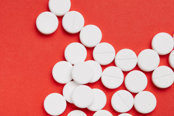 istock A few white round pills on the red paper background. 1003597568