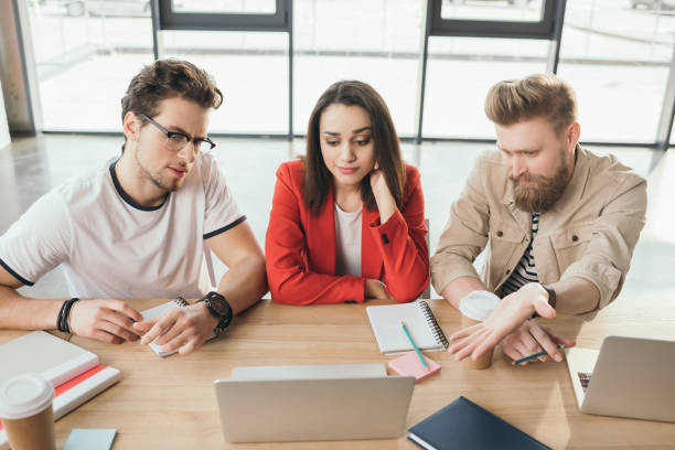 istock Thoughtful business team looking at laptop in light workspace 1003598716