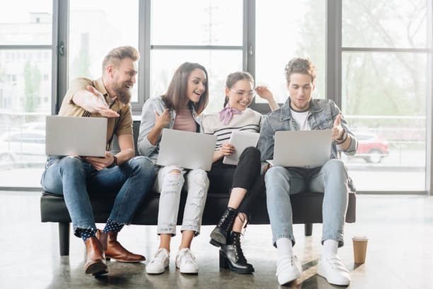 istock Professional business colleagues men and women working on laptops while sitting on sofa in modern office 1003598984
