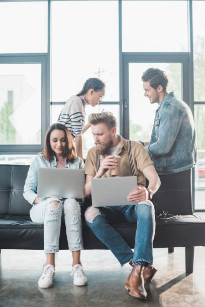 istock Successful business people working on laptops and discussing project in modern light office 1003599008