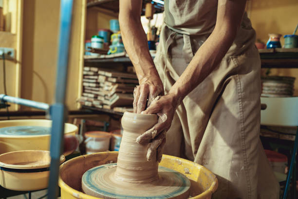 istock Creating a jar or vase of white clay close-up. Master crock. Man hands making clay jug macro 1003609714