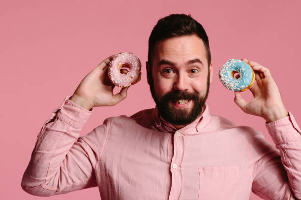 istock Smiling man holding a blue and pink donut 1003611292
