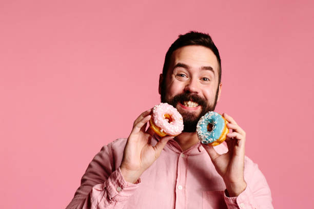 istock Sweet tooth bliss : Smiling man holding a blue and pink donut 1003611316