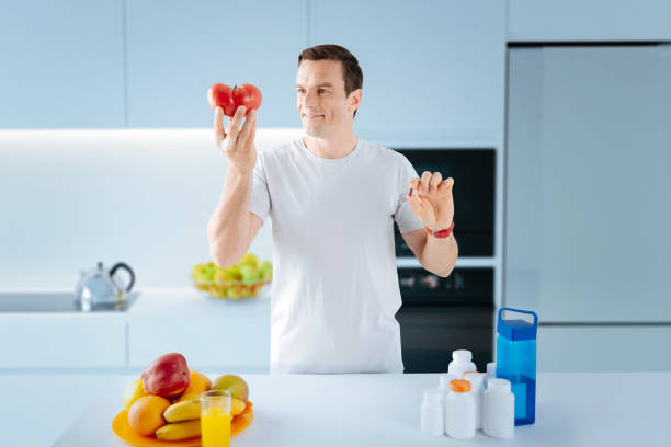 istock Smiling man looking at the big tomato and holding a pill 1003623236