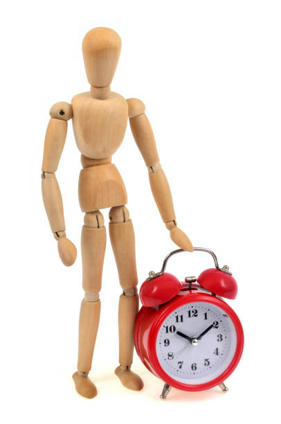 istock Wooden mannequin next to a morning alarm clock 1003625042