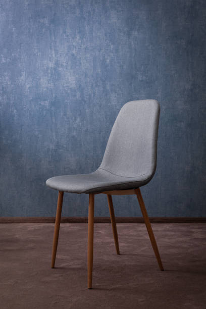 Grey modern textile chair with wood on a background of a wall. Good concept for hotel.