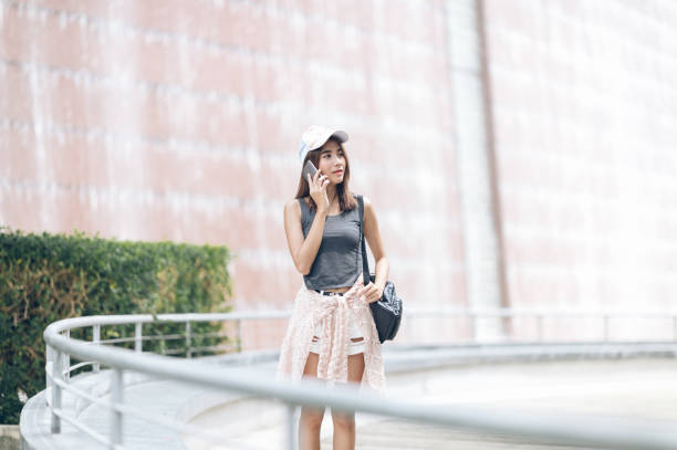 istock Asian young woman standing at park using mobile phone,Woman write text message on mobile phone ,Happy beautiful girl using smartphone,Girl texting smartphone concept 1003651686