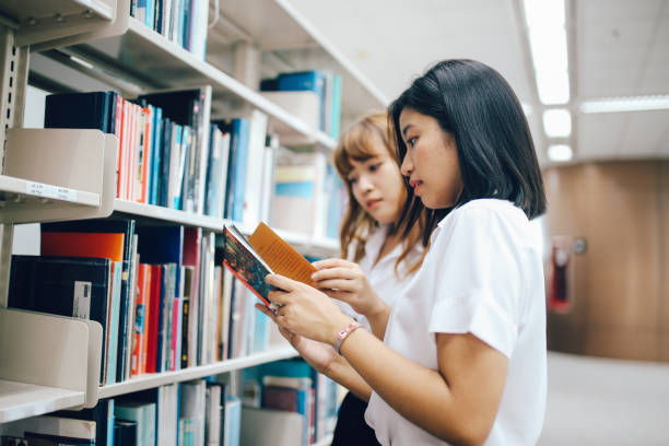 istock Two young Asian students searching for books in the library 1003673046