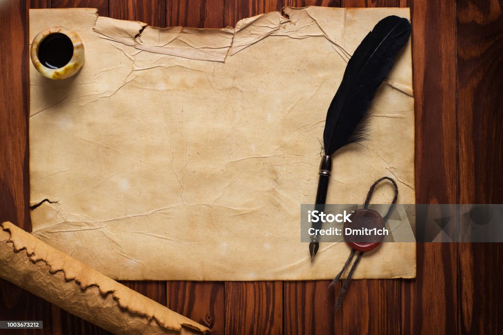 White goose feather and inkwell, scroll on the background table black quill pen and ink on old paper background Parchment Stock Photo