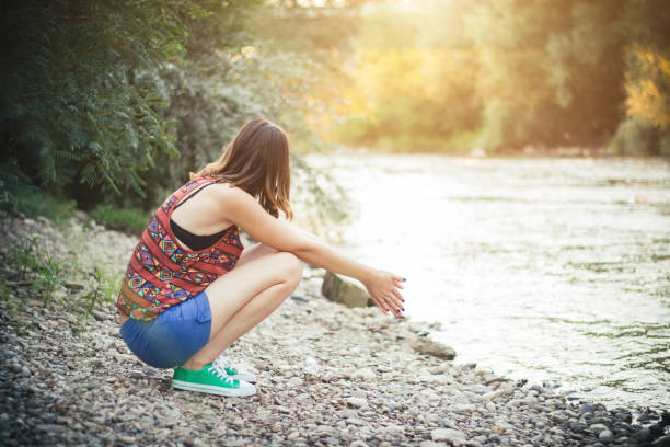 istock Girl squatting by the river 1003673312