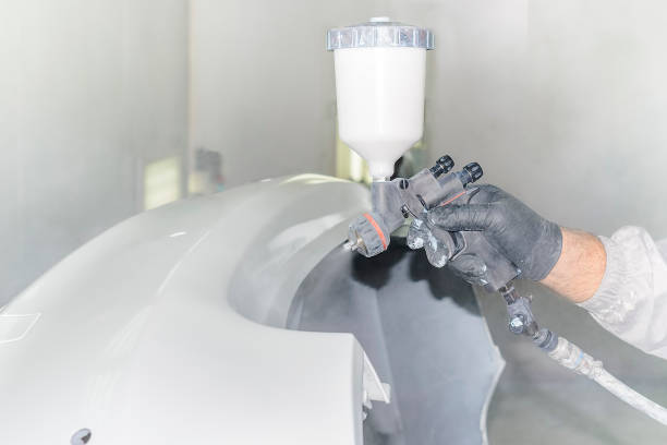 istock Man's hand with airbrush paints car parts 1003689214