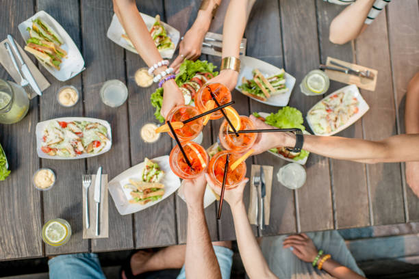 Table full of snacks and drinks Friends clinking glasses with cocktail drinks, top view on the table full of snacks outdoors aperitif photos stock pictures, royalty-free photos & images