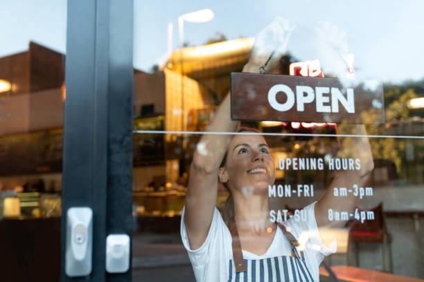 幸せなビジネスの所有者がカフェでオープン サインをぶら下げ - 開いている ストックフォトと画像