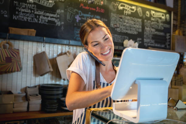 Waitress talking on the phone at a restaurant Waitress talking on the phone at a restaurant taking a delivery order and looking happy - food service concepts waitress stock pictures, royalty-free photos & images