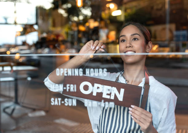 istock Happy waitress hanging an open sign at a cafe 1003743934