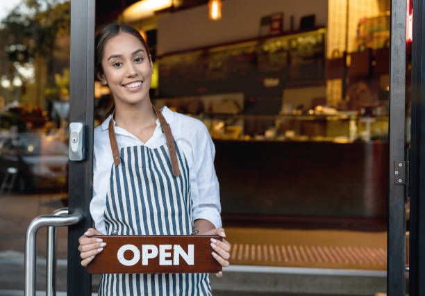 istock Happy waitress holding an open sign at a cafe 1003743948