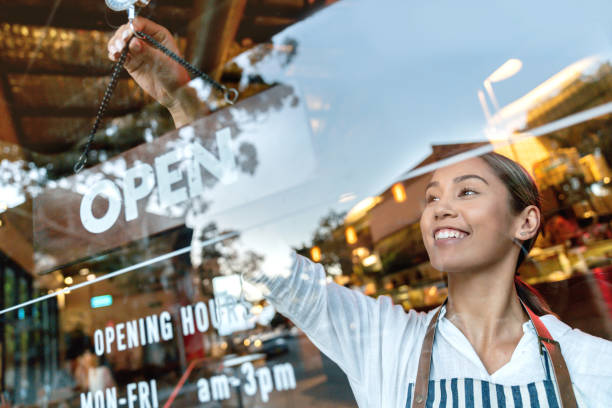 istock Happy waitress hanging an open sign at a restaurant 1003743968