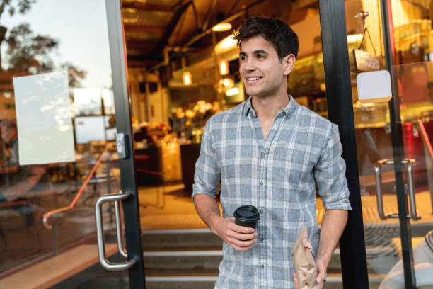 istock Man exiting a cafe carrying coffee to go 1003747594