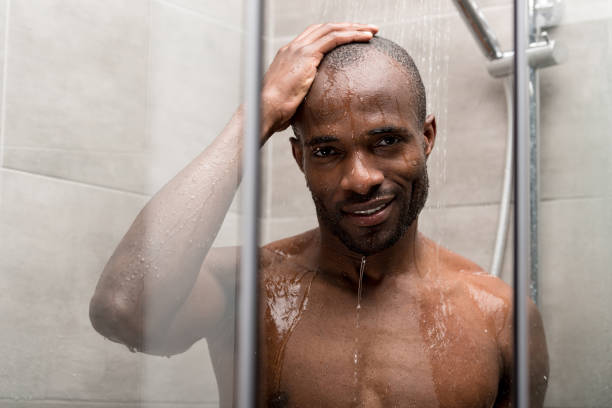 istock handsome african american man taking shower and smiling at camera 1003751632