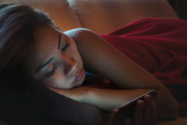 istock Asian woman using mobile phone on couch before falling sleep 1003759188