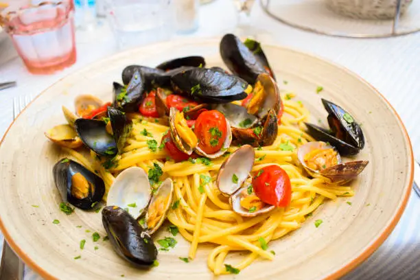 Photo of Italian pasta with seafood, herbs and cherry tomatoes.