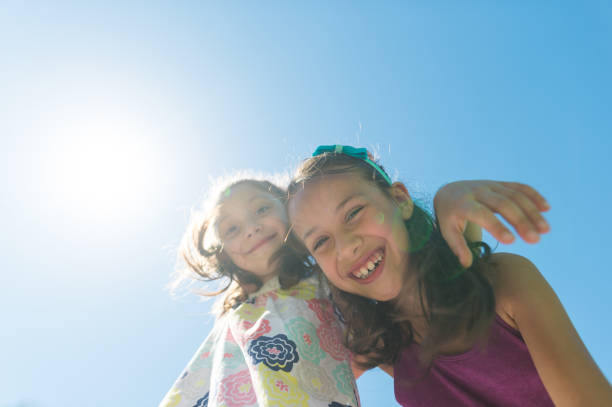istock Two elementary-age girls posing together at the park on a sunny day 1003772520