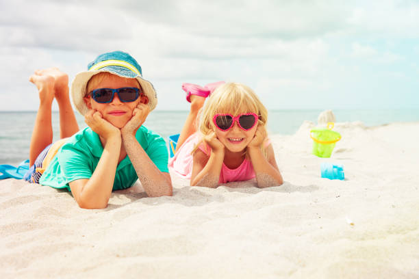 istock cute boy and girl play with sand on beach 1003782994