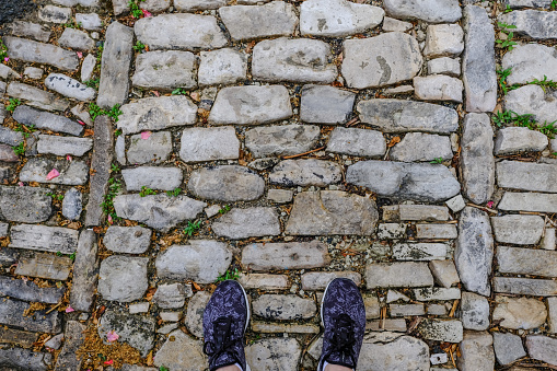 Pair of feet in shoes on an old cobbled path.  Start of a new journey.