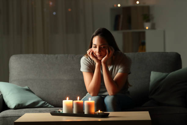 istock Distracted woman looking at candles light during blackout 1003789054