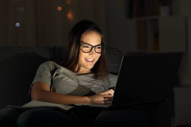 istock Woman wearing eyeglasses using a laptop in the night 1003790284