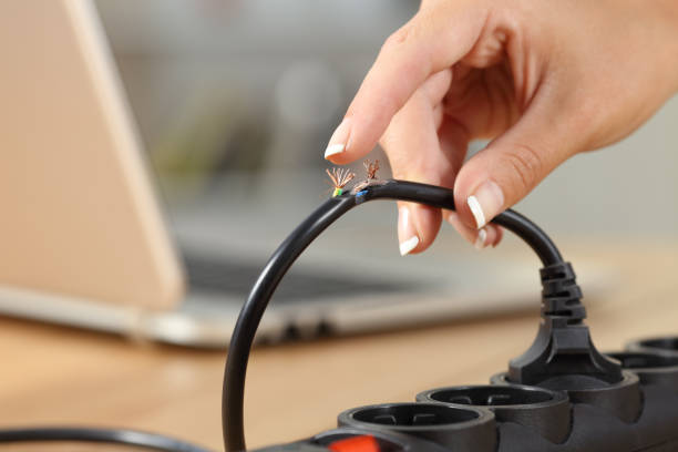 Hand holding a dangerous damaged electrical cord Close up of a woman hand holding a dangerous damaged electrical cord unsafe workplace stock pictures, royalty-free photos & images