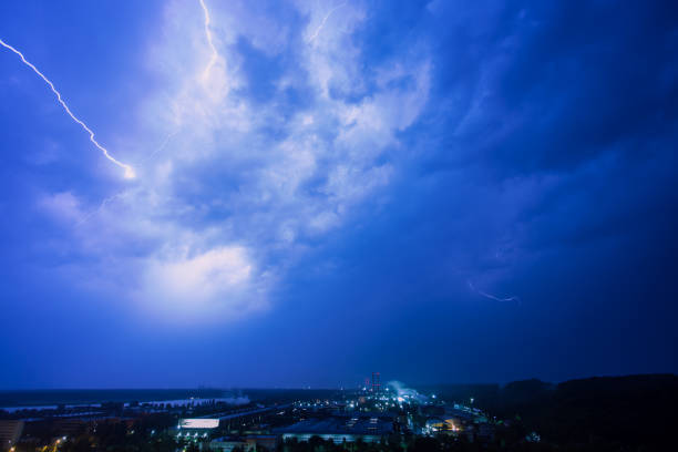istock Thunderstorm with lightning above industrial district at night. 1003790660