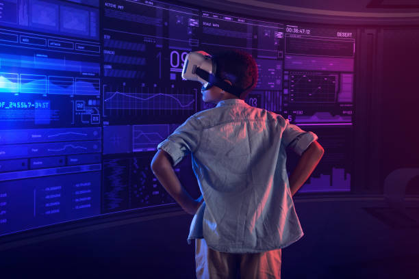 istock Serious boy wearing virtual reality glasses and putting his hands on the hips 1003791604