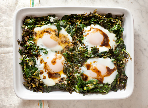 Baked eggs and spinach with spiced butter in a casserole dish