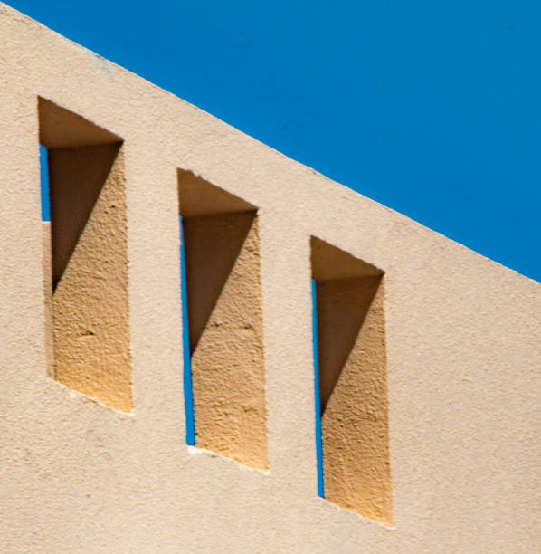 istock Three simple stone window in the sandstone wall with blue sky at daytime 1003801490