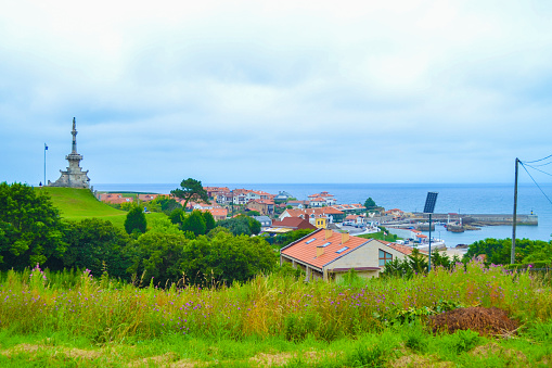 View of port of Comillas and Guell y Martos park, with Monument of Marquis of Comillas (Monumento al Marques de Comillas) at the background, in Comillas, Cantabria, Spain