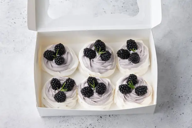 Photo of Set of Pavlova cakes with blackberries in white box