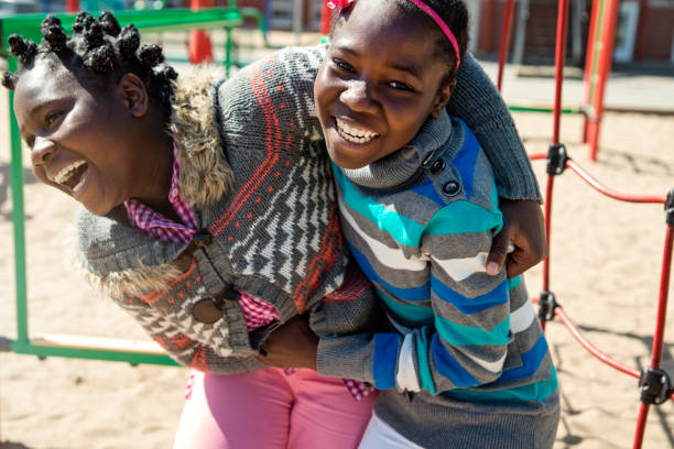 deux filles jumelles afro-américaine jouant dans la cour de récréation à la récréation... - schoolyard photos et images de collection