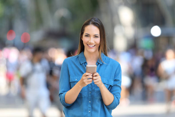 istock Woman holding smart phone looks at camera 1003816490