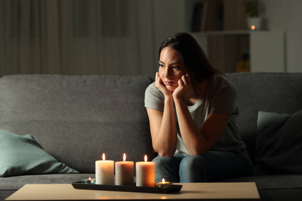 Frustrated woman sitting at home during a blackout Frustrated woman sitting at home during a blackout sitting on a couch in the living room at home blackout photos stock pictures, royalty-free photos & images
