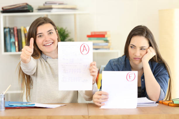 Students with failed and approved exams Front view portrait of two students showing failed and approved exams at home unliked stock pictures, royalty-free photos & images