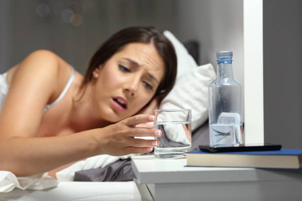 dehydrated woman reaching a glass of water - thirsty imagens e fotografias de stock