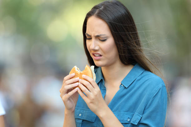 frau einen burger mit schlechtem geschmack essen - eating sandwich emotional stress food stock-fotos und bilder