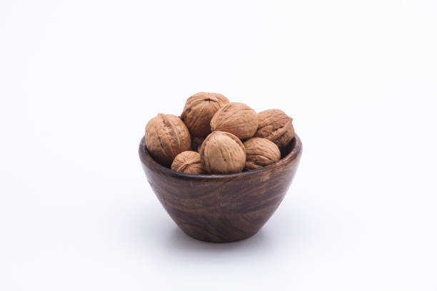 istock Walnuts in wooden bowl isolated on white background 1003823066