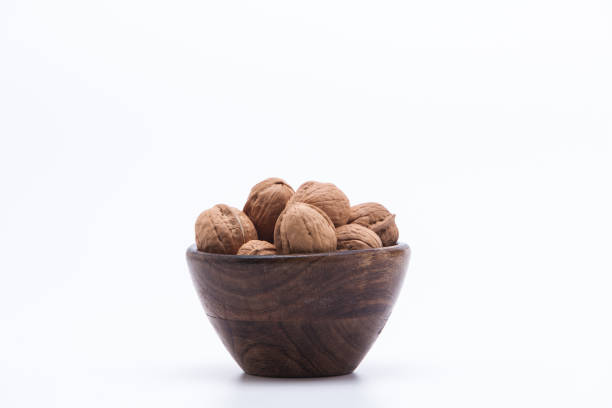 istock Walnuts in wooden bowl isolated on white background 1003823068