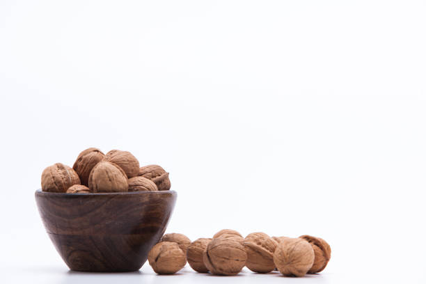 istock Walnuts in wooden bowl isolated on white background 1003823086