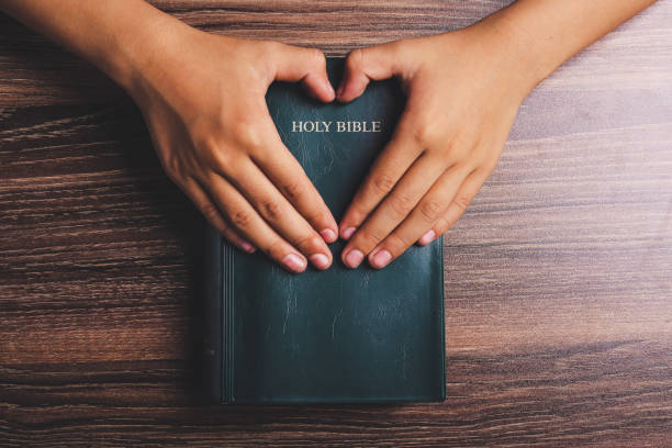 istock Holy bible with heart shape hands 1003824116