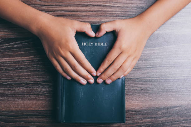 istock Holy bible with heart shape hands 1003824206